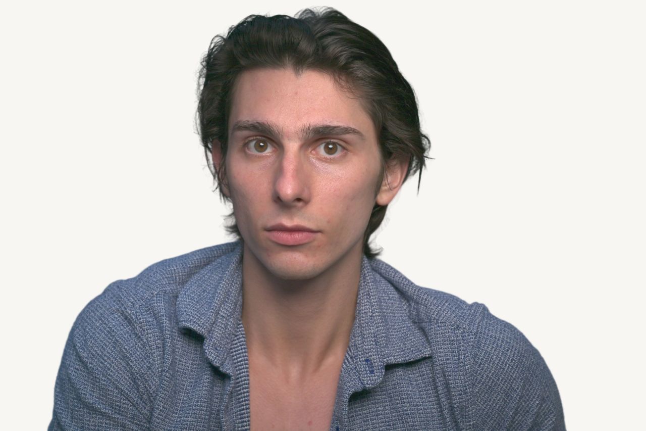 Tristan Colt, direct. Tristan Colt looking straight into the camera, neutral expression, open-collar blue shirt.