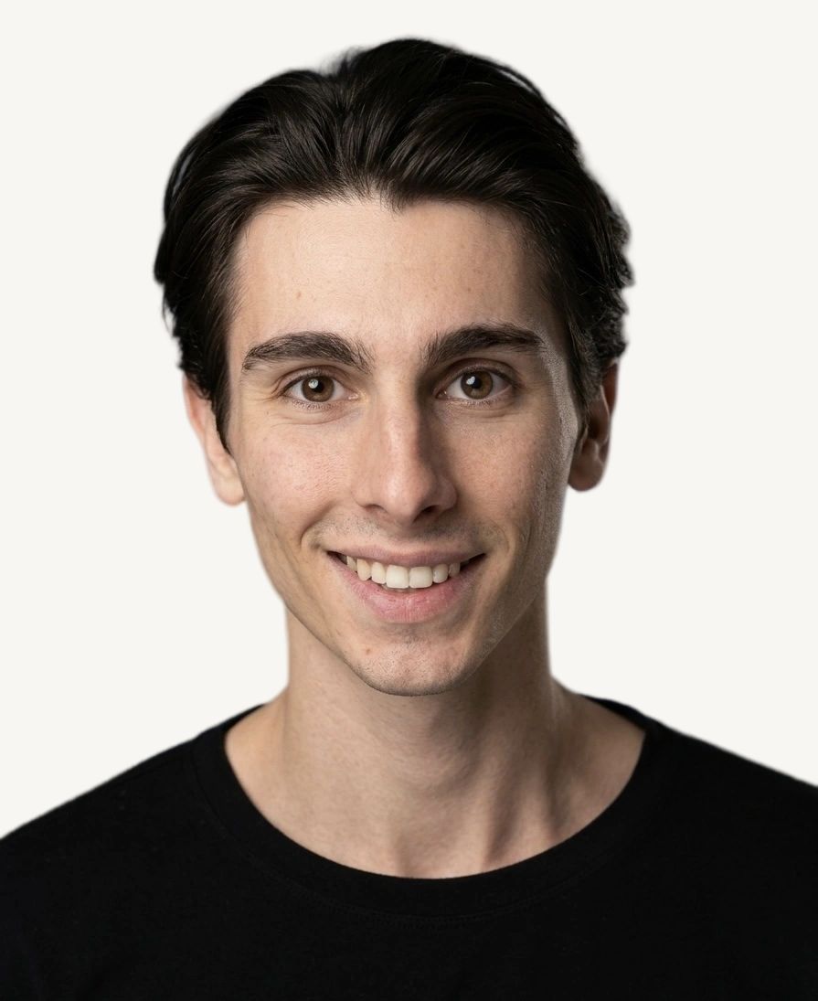 Tristan Colt, commercial. Tristan Colt smiling broadly at the camera, short dark hair, black t-shirt.