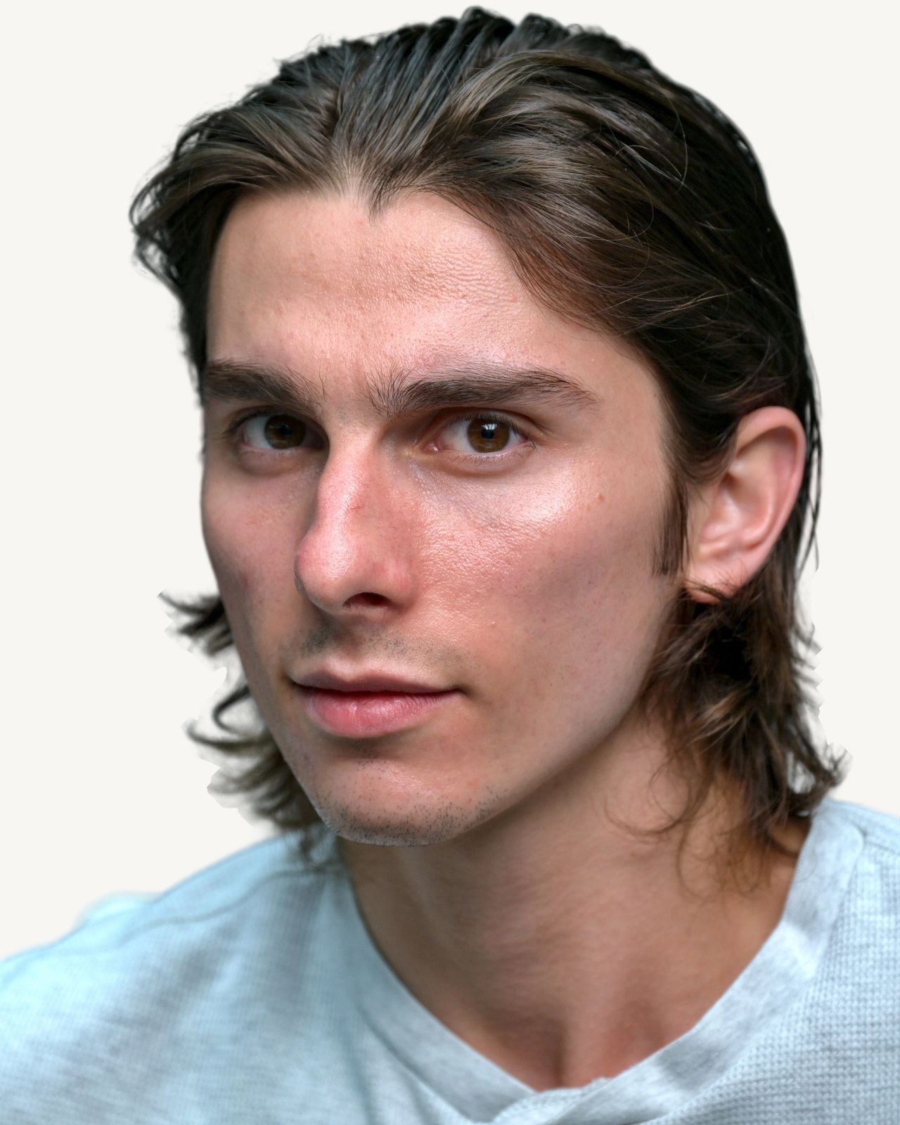 Tristan Colt, intense. Tristan Colt in close-up, head tilted, looking into the camera with an intense gaze, long hair swept back, white t-shirt.